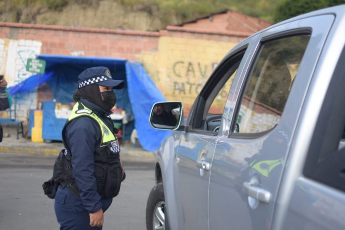 Una guardia municipal conversa con un conductor de un vehículo en la frontera de restricción. Foto: AMUN